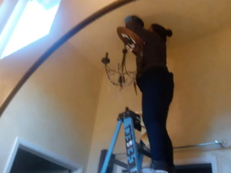 Electrician installing a chandelier in a Bloomfield residence